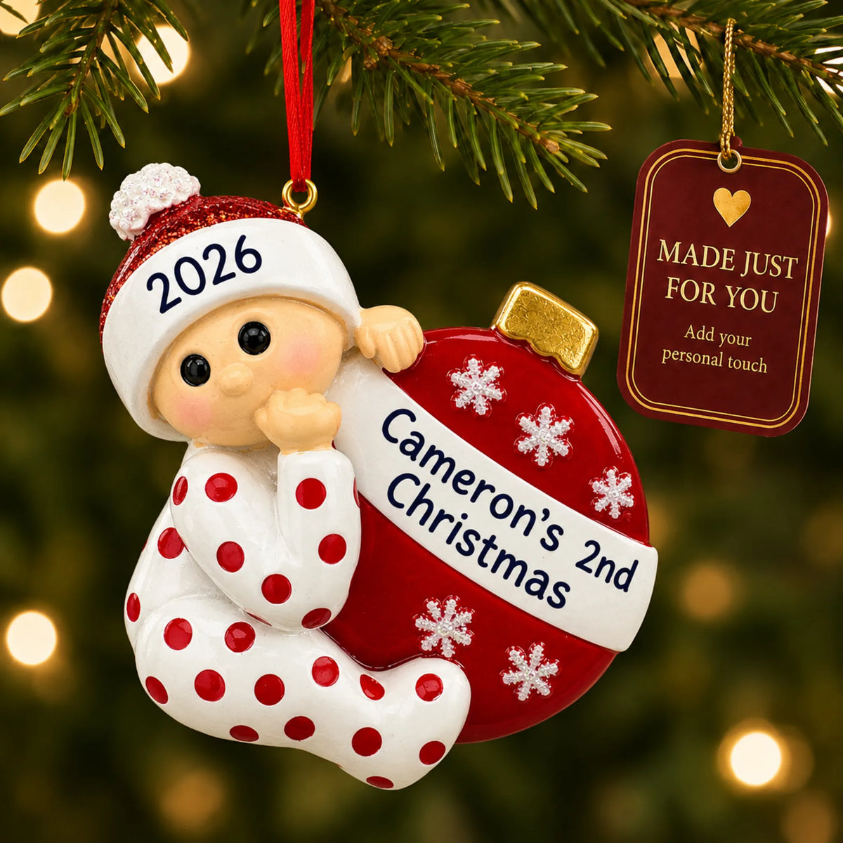 Red baby's 2nd christmas ornament hanging on a lit Christmas tree with a Made Just For You gift tag