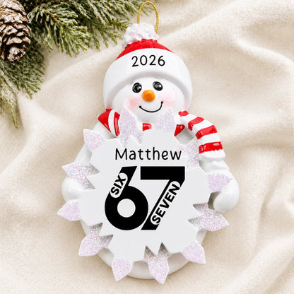 Personalized 6 7 viral slang christmas ornament laid on a soft white knit blanket