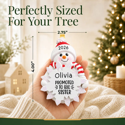 Size guide: the personalized promoted to big sister christmas ornament shown in hand next to a Christmas tree