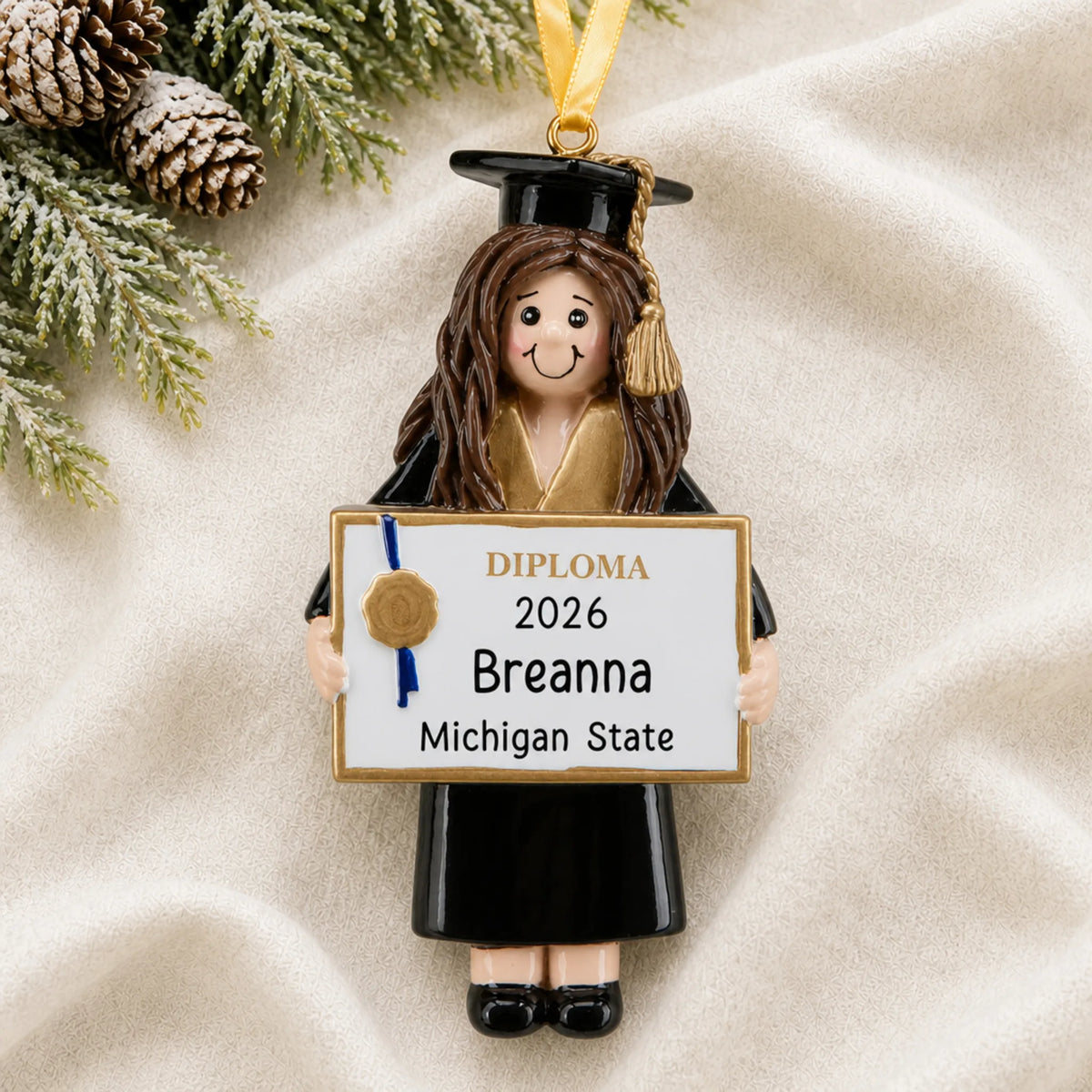 Personalized graduation girl Christmas ornament with diploma, name and year, shown on a soft white blanket