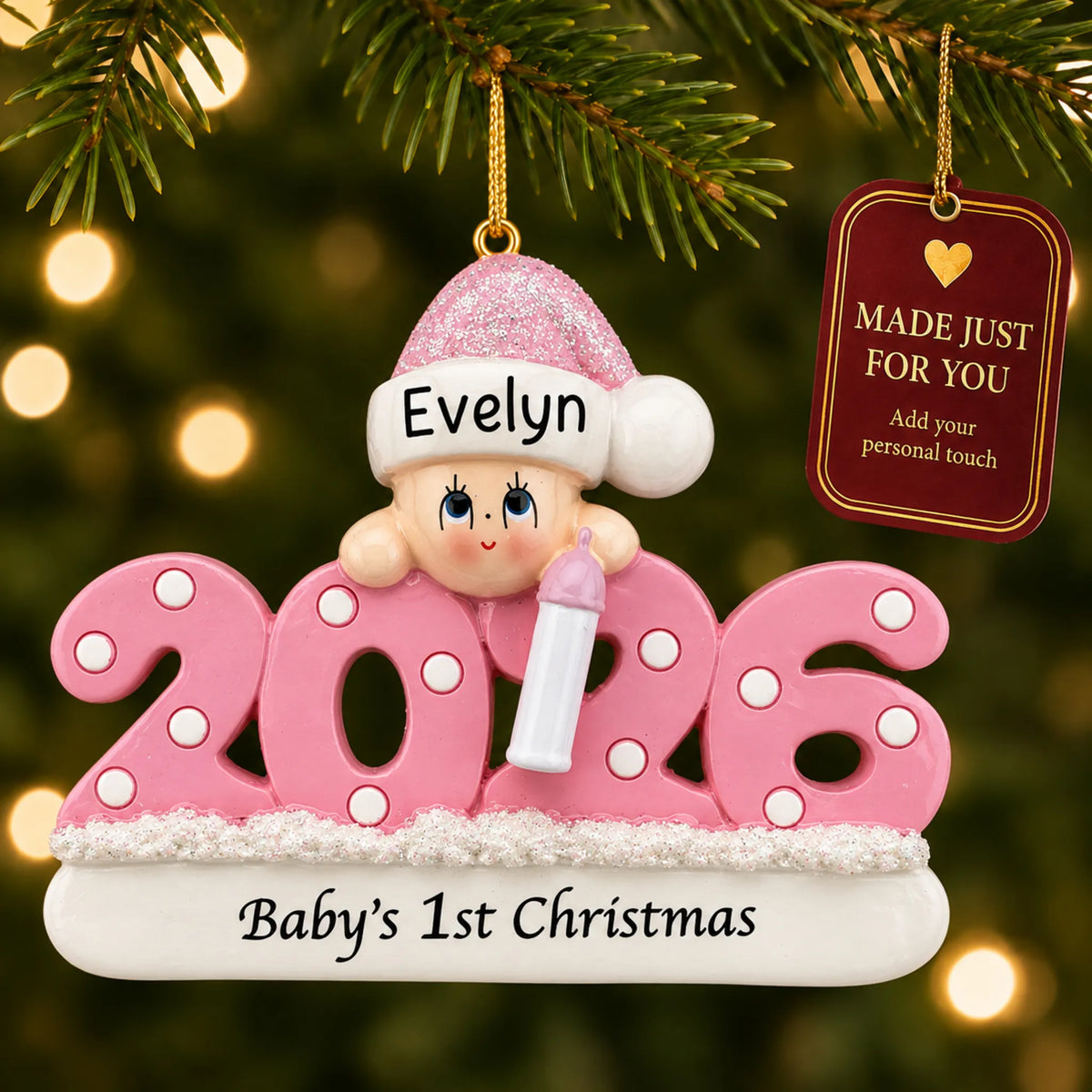 Baby girl's 1st christmas 2026 ornament hanging on a lit Christmas tree with a Made Just For You gift tag
