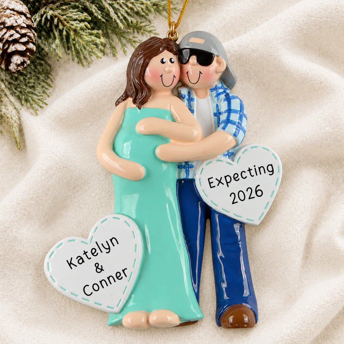 Personalized Expecting Couple christmas ornament laid on a soft white knit blanket