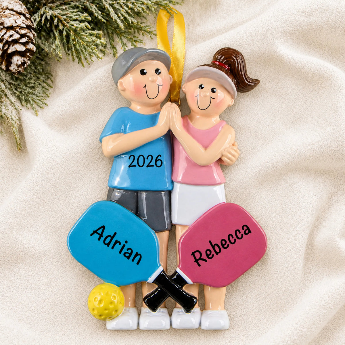 Personalized pickleball couple christmas ornament laid on a soft white knit blanket
