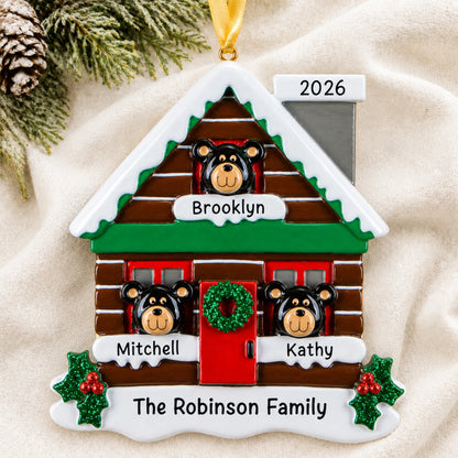 Personalized mountain cabin family of 3 christmas ornament laid on a soft white knit blanket