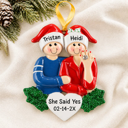 Personalized Engaged Couple christmas ornament laid on a soft white knit blanket