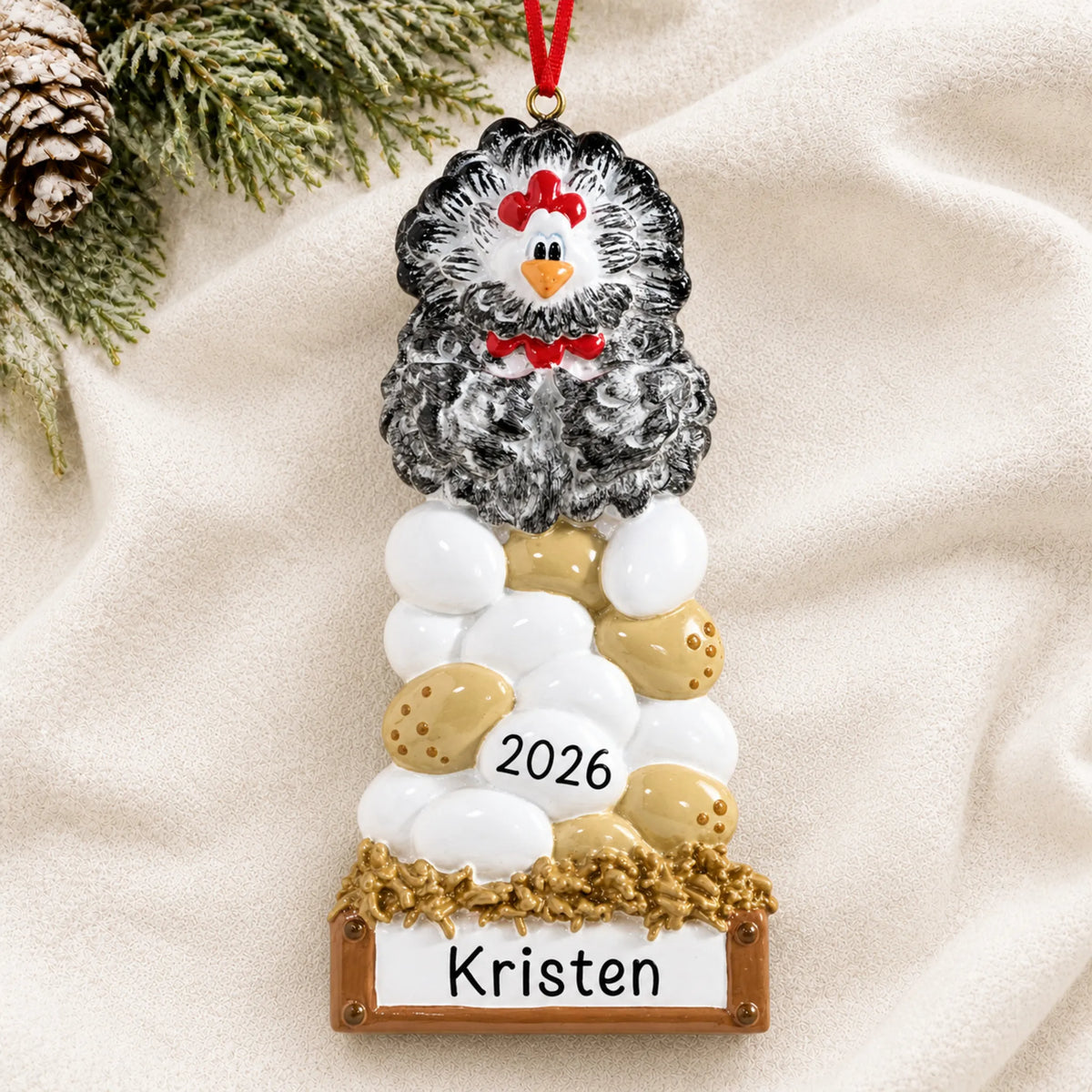 Personalized chicken laying eggs christmas ornament laid on a soft white knit blanket