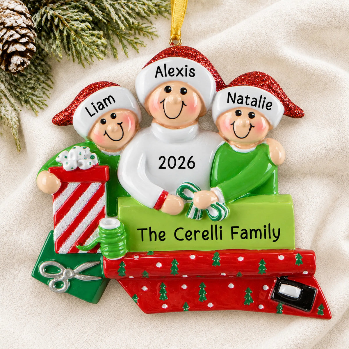 Personalized single parent & 2 children christmas ornament laid on a soft white knit blanket