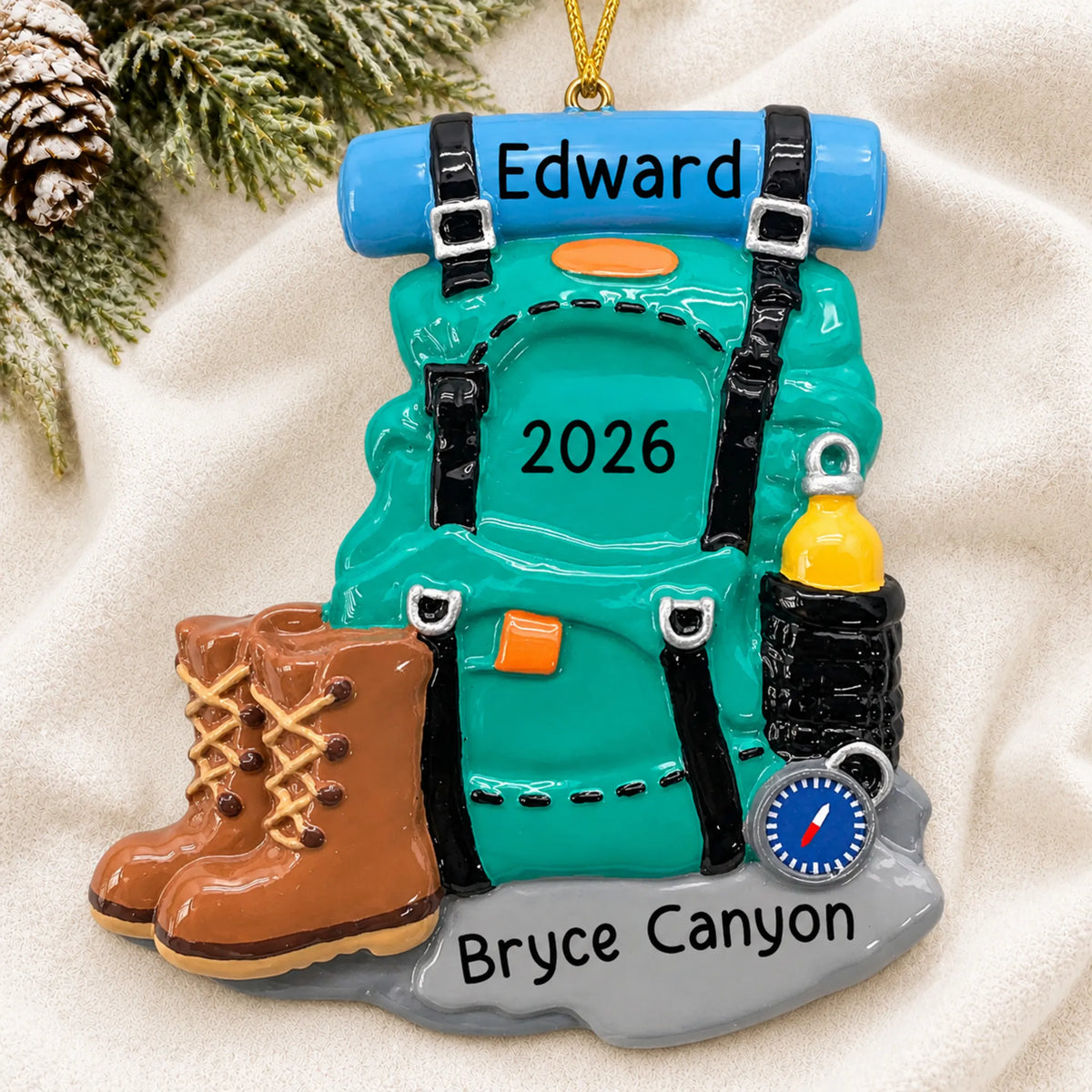 Personalized hiking backpack christmas ornament laid on a soft white knit blanket