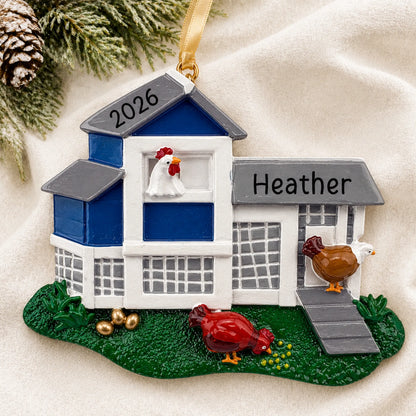 Personalized chicken coop christmas ornament laid on a soft white knit blanket