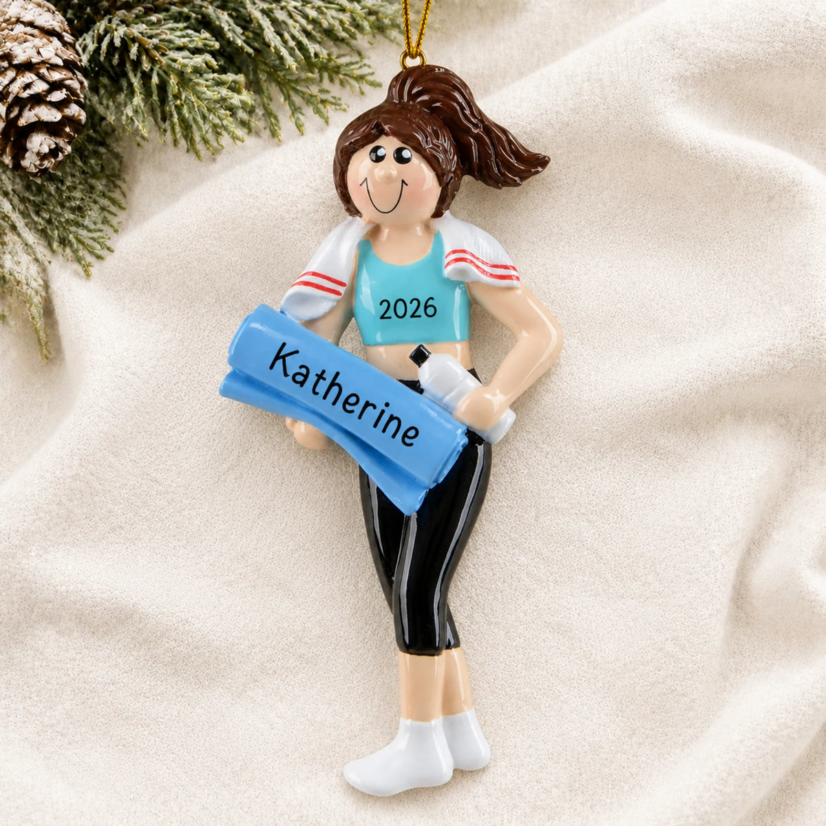 Personalized yoga girl christmas ornament laid on a soft white knit blanket