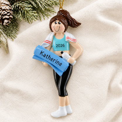 Personalized yoga girl christmas ornament laid on a soft white knit blanket