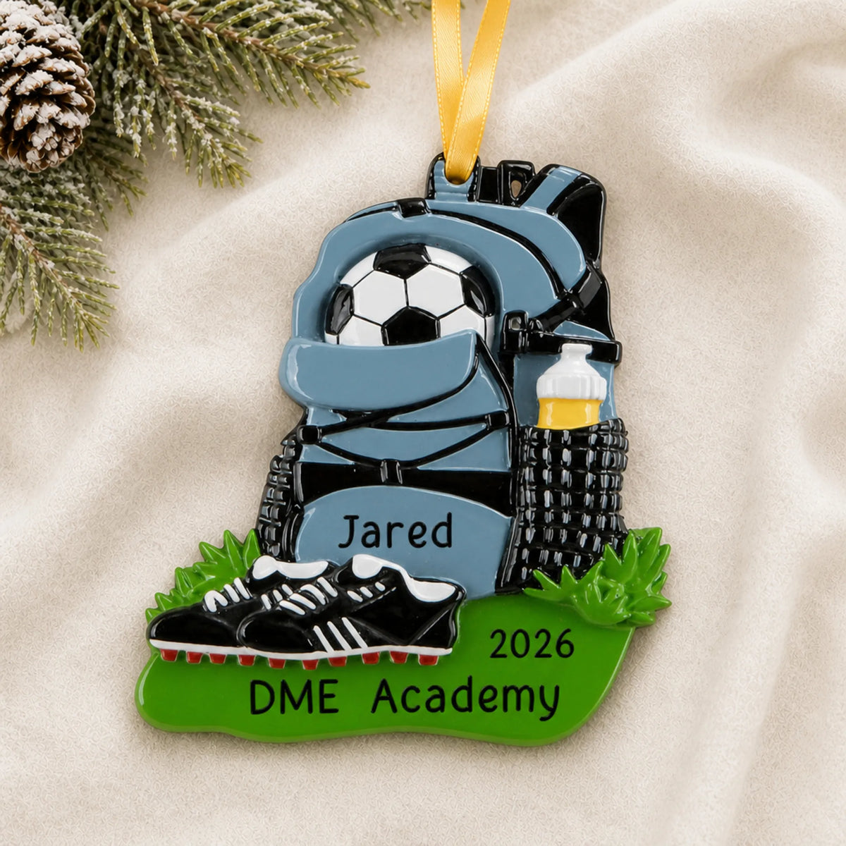 Personalized soccer gear christmas ornament laid on a soft white knit blanket