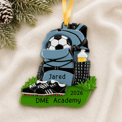 Personalized soccer gear christmas ornament laid on a soft white knit blanket