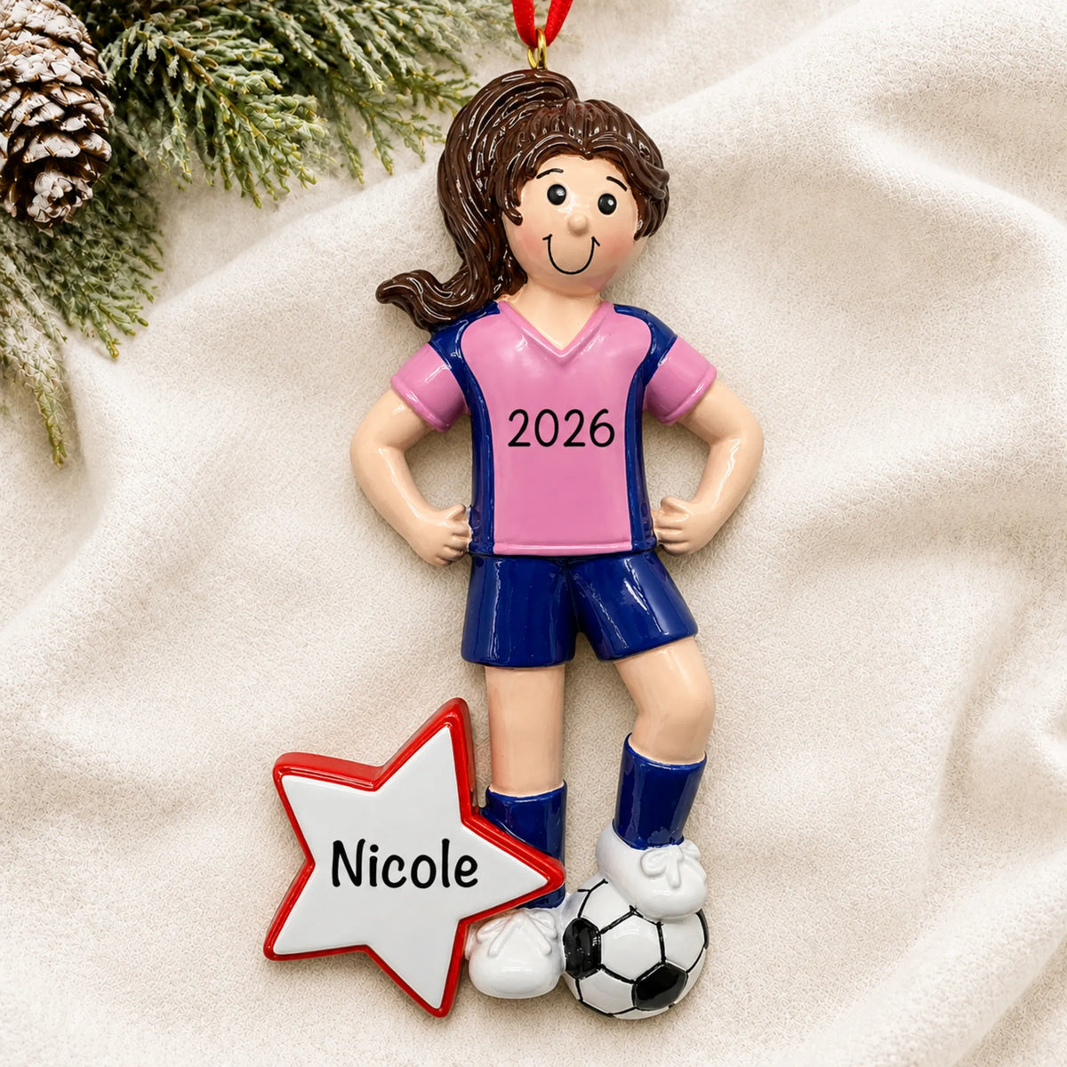 Personalized soccer all-star girl christmas ornament laid on a soft white knit blanket