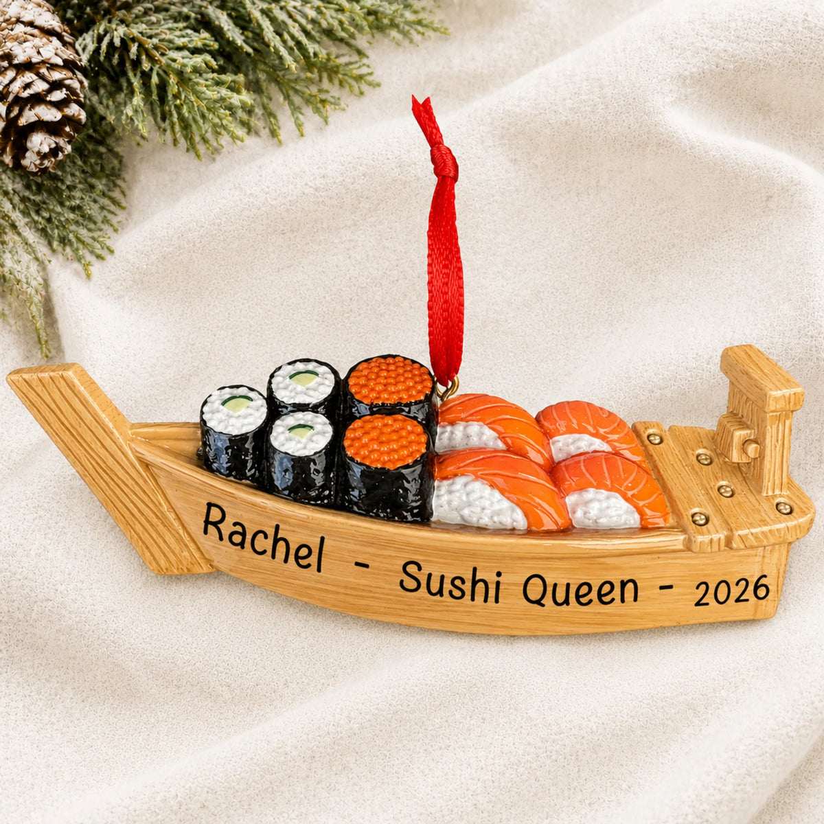 Personalized Sushi Boat christmas ornament laid on a soft white knit blanket