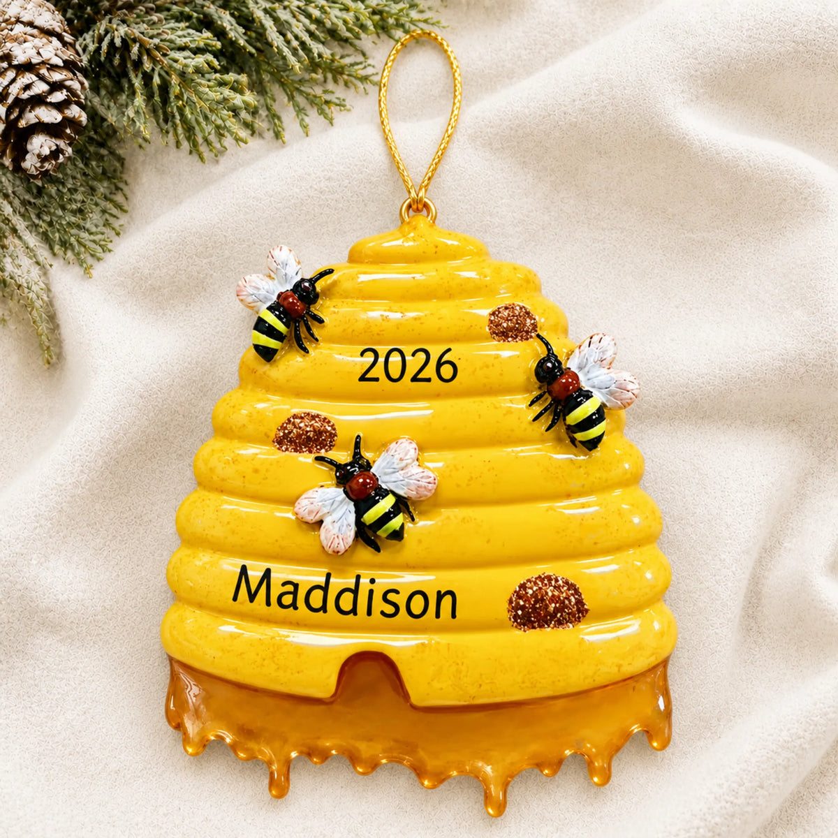 Personalized honey beehive christmas ornament laid on a soft white knit blanket