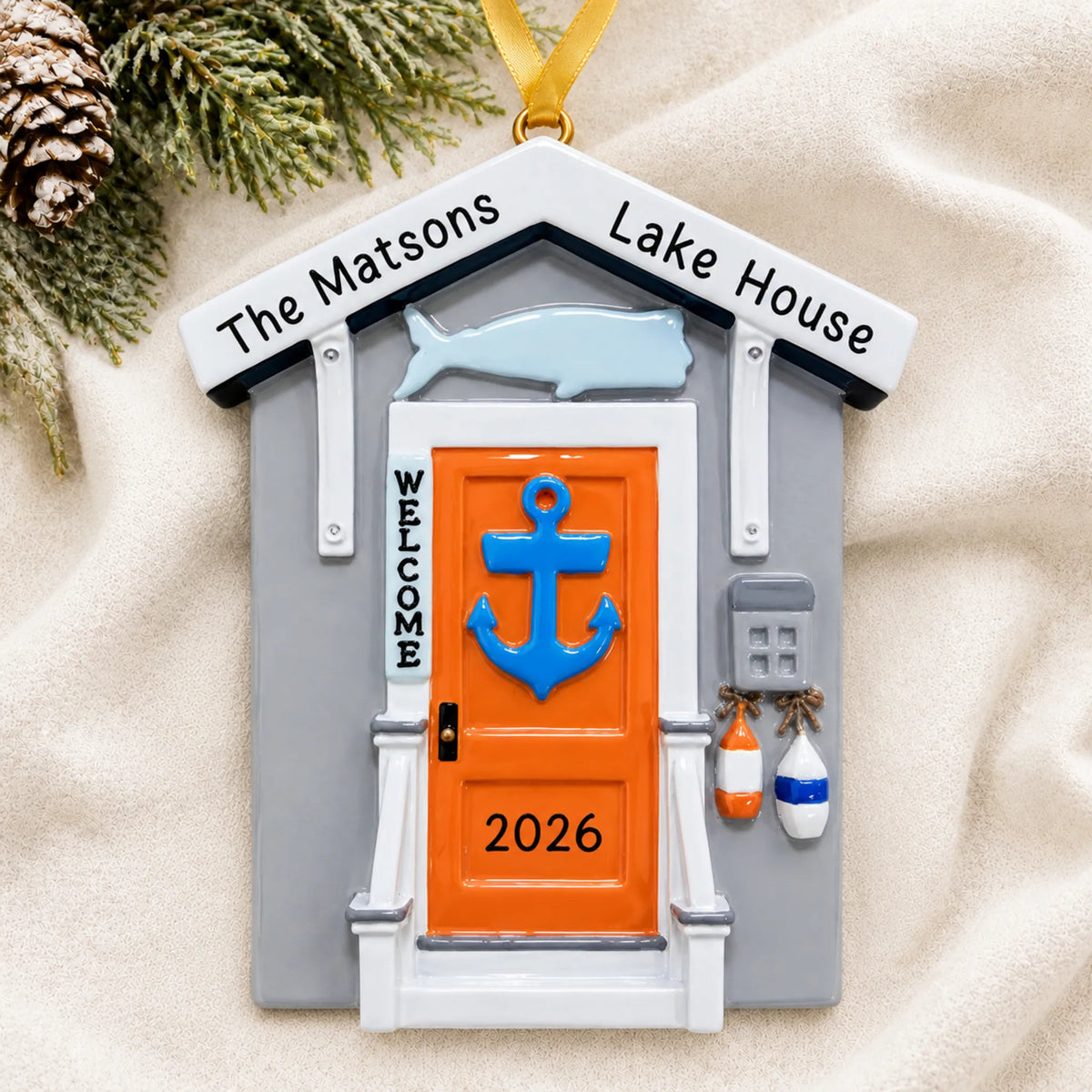 Personalized Lake House christmas ornament laid on a soft white knit blanket
