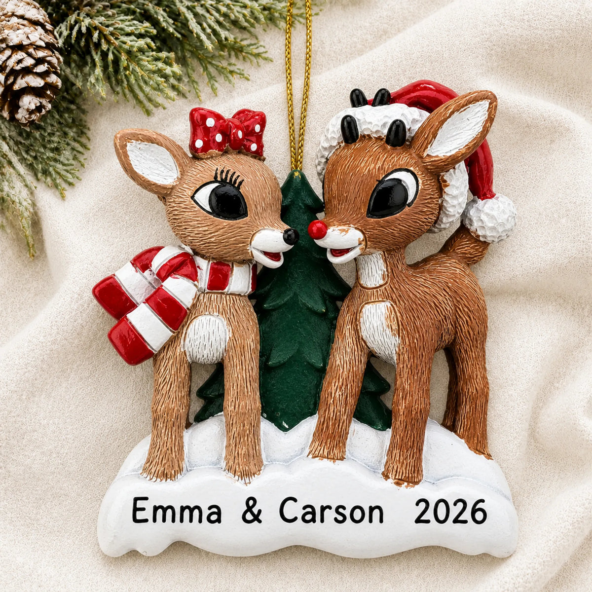 Personalized Rudolph and Clarice christmas ornament laid on a soft white knit blanket