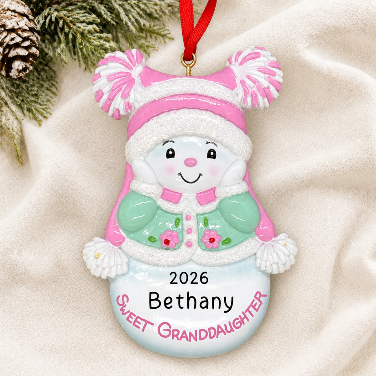 Personalized sweet granddaughter christmas ornament laid on a soft white knit blanket