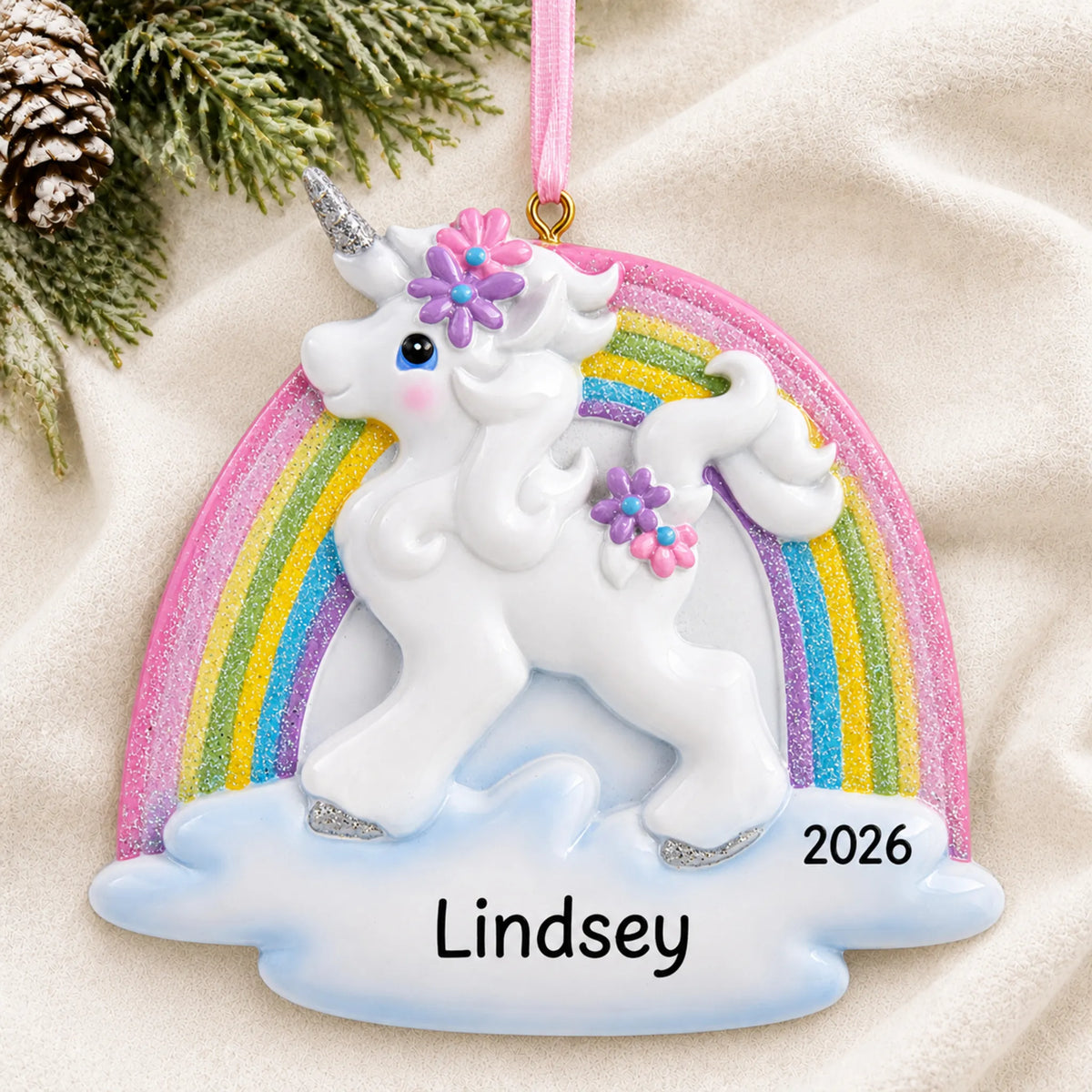 Personalized unicorn rainbow christmas ornament laid on a soft white knit blanket