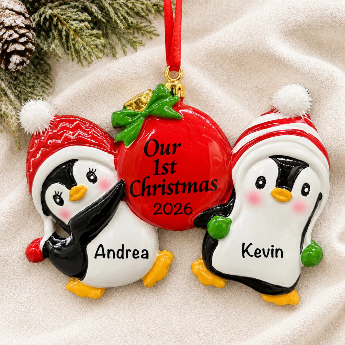 Personalized our first christmas penguins ornament laid on a soft white knit blanket