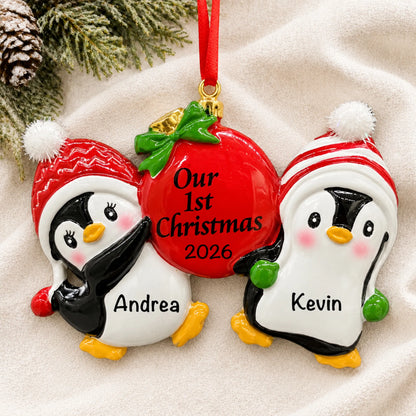 Personalized our first christmas penguins ornament laid on a soft white knit blanket