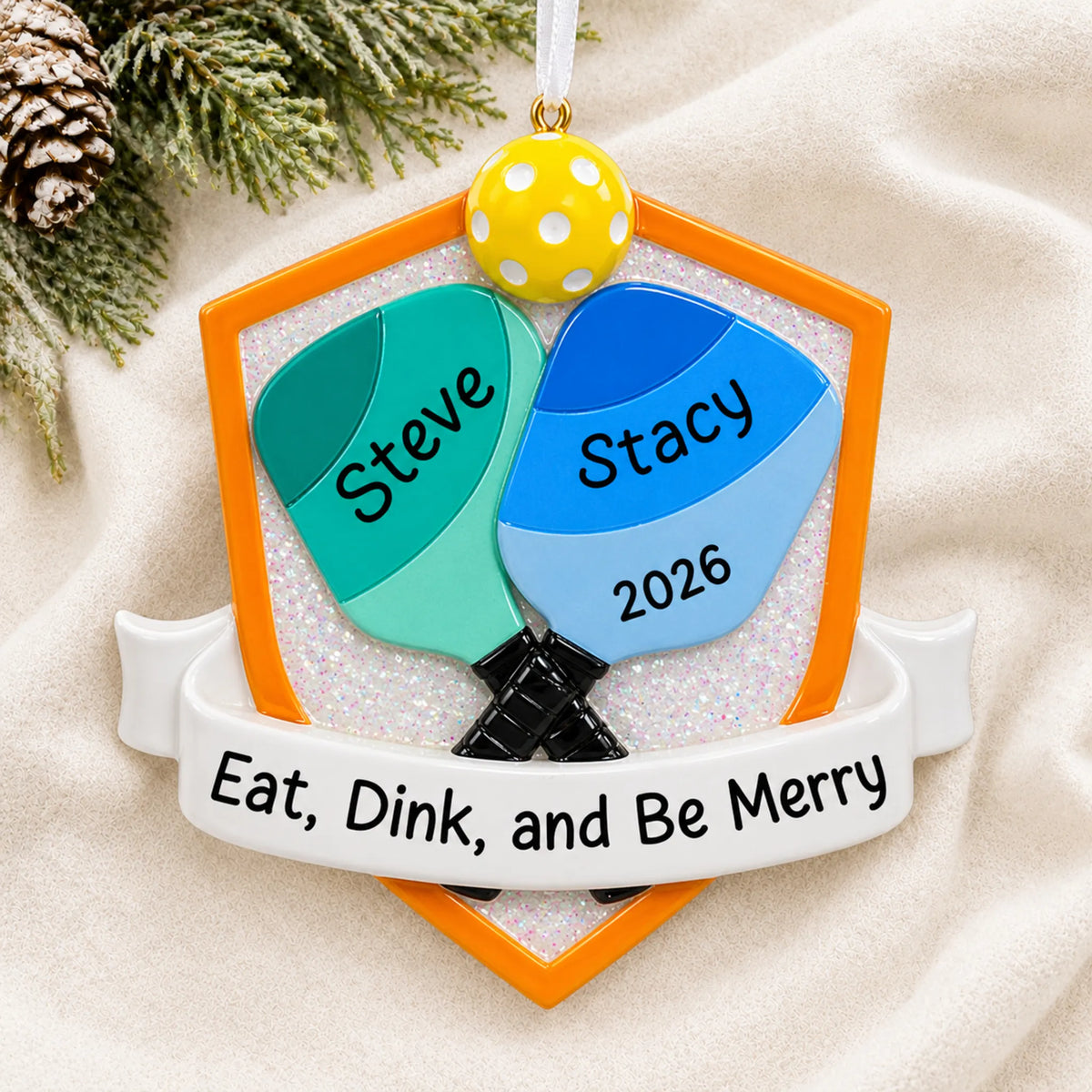 Personalized pickleball doubles christmas ornament laid on a soft white knit blanket